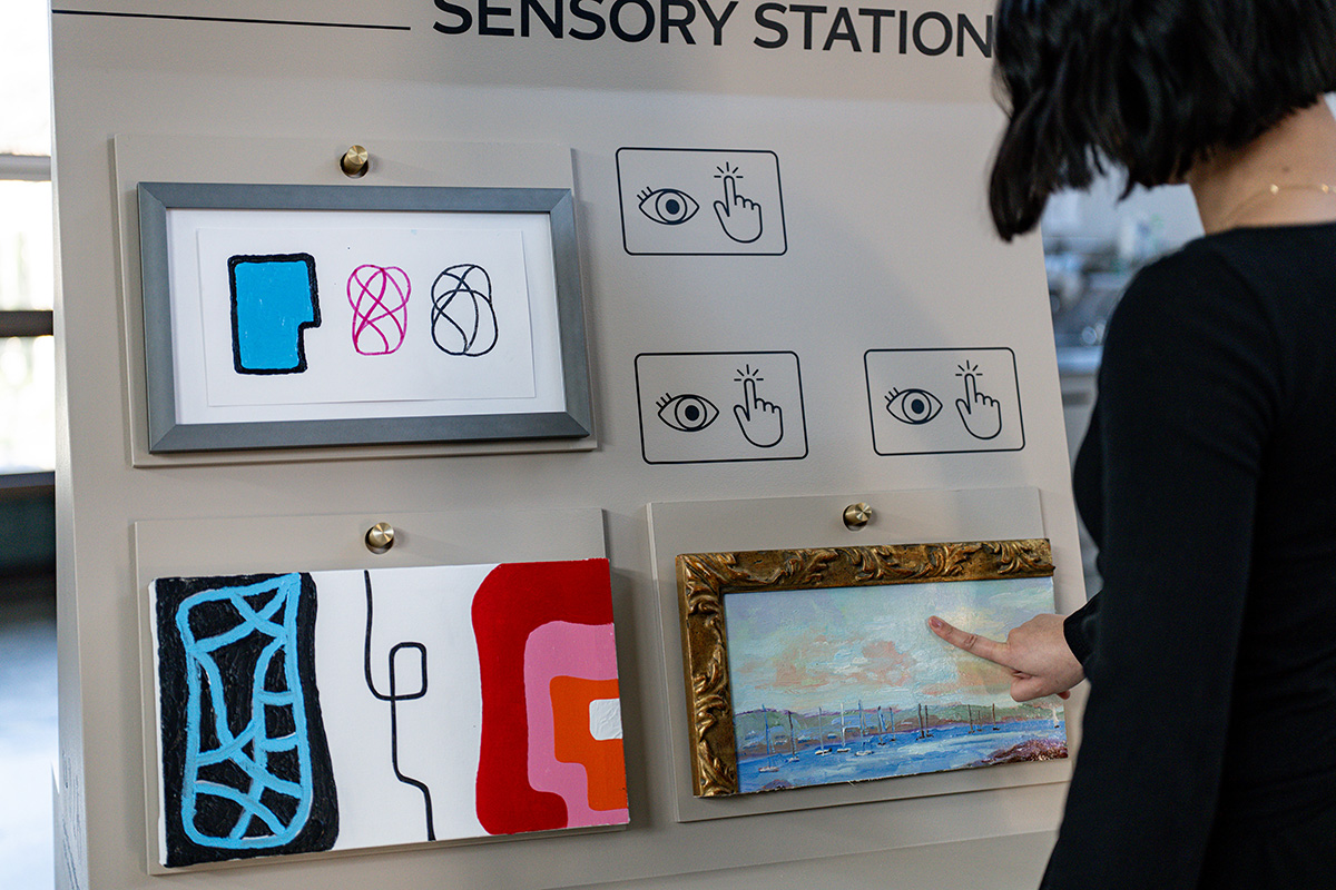 A person touching a sample of an oil painting on a mobile cart
