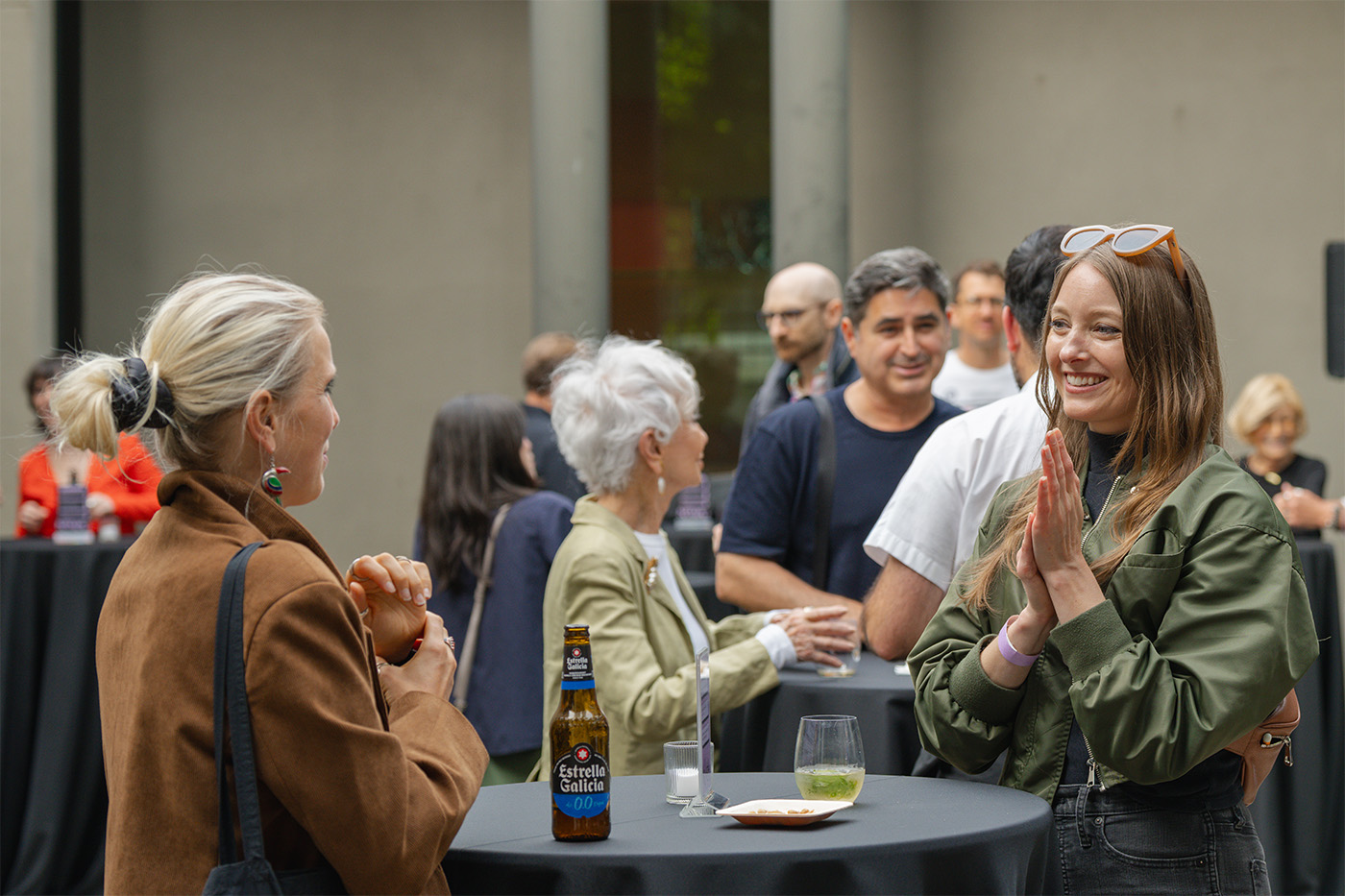 People standing and chatting outside in a courtyard around small tables
