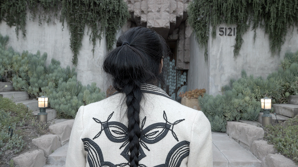 A still from a video of a women's back approaching two stairways