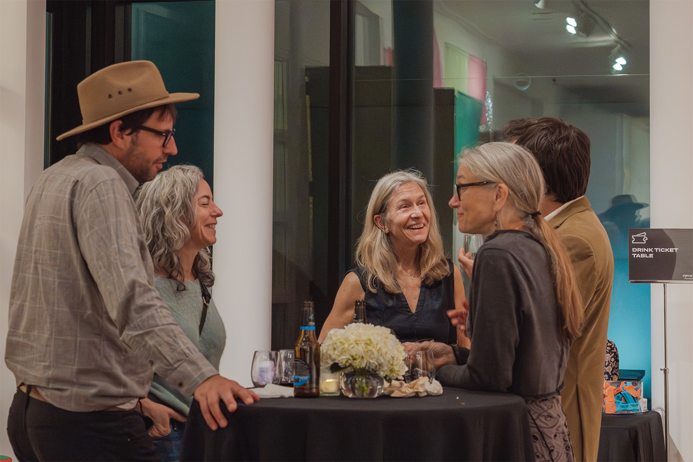 A group of people standing around a tall table and chatting