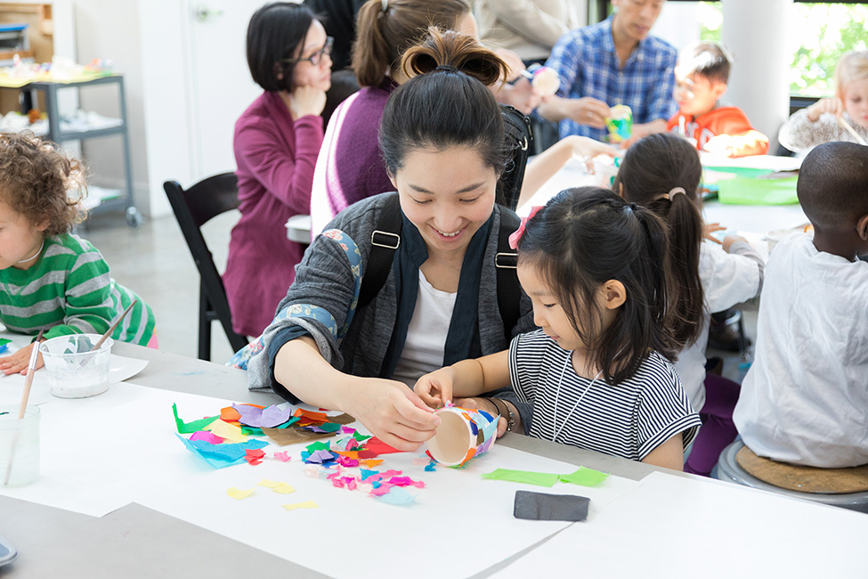 A person helps a child with an art project