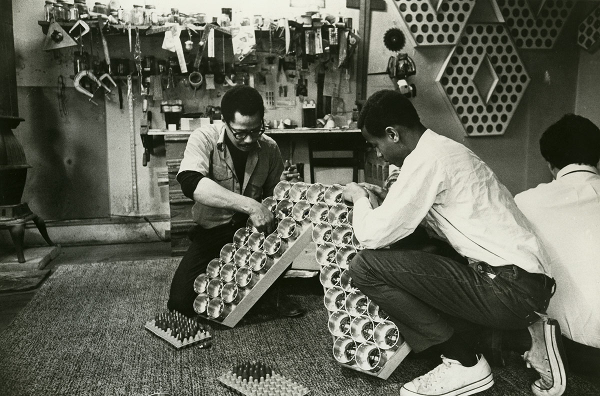 An old, black and white film photo of men crouching around and working on an electronic light display