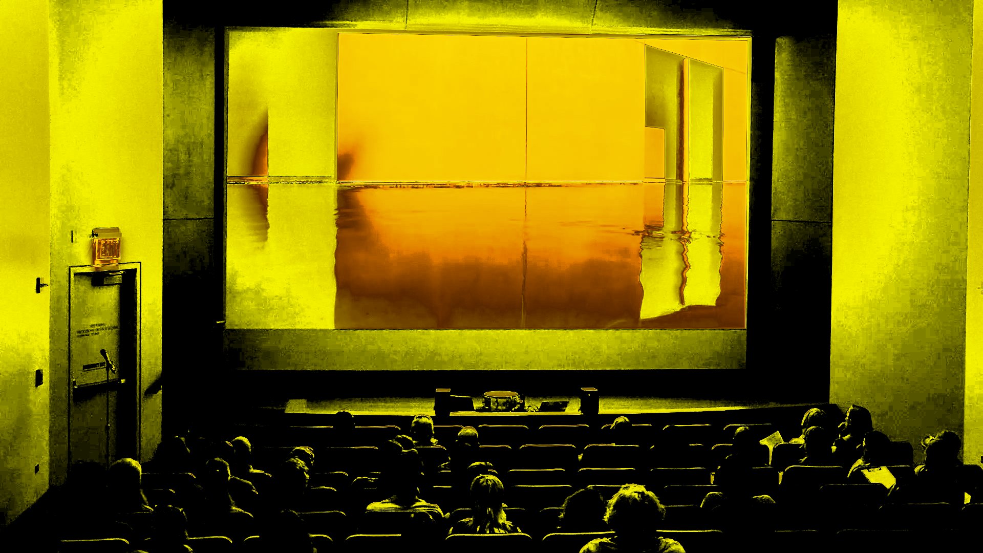 A photo of an indoor auditorium stage that is digitally manipulated with bright yellows and glitchy effects 