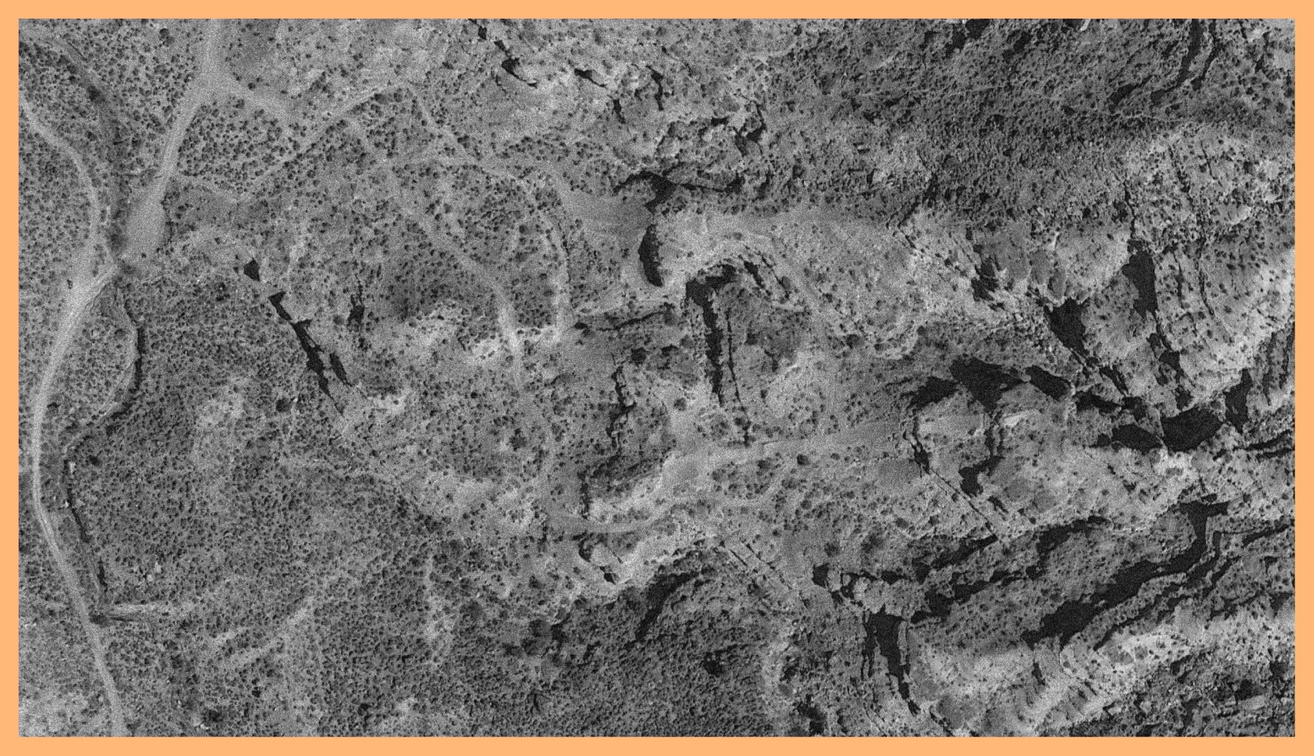 Black and white photograph of a mountain surface taken in Virgin, Utah. The image is surrounded by an orange border.