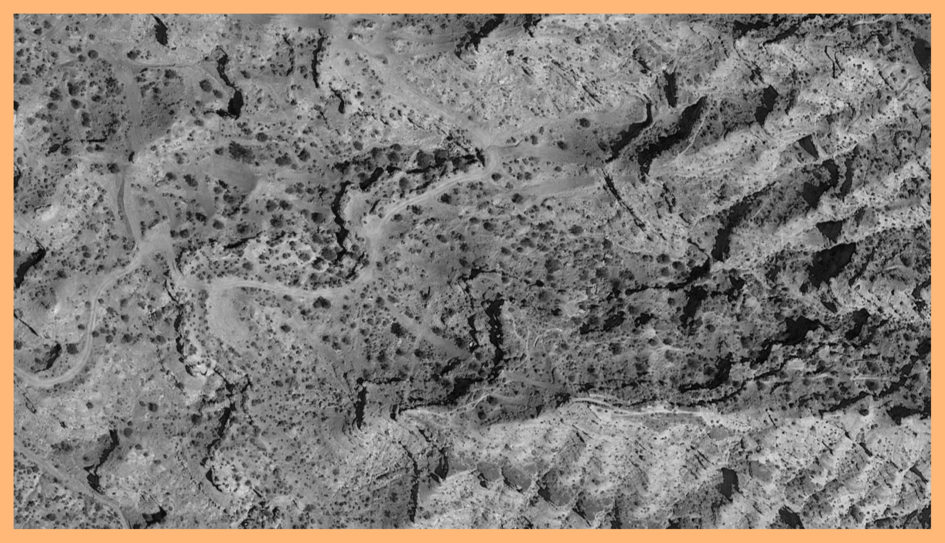 Black and white photograph of a mountain surface taken in Virgin, Utah. The image is surrounded by an orange border.