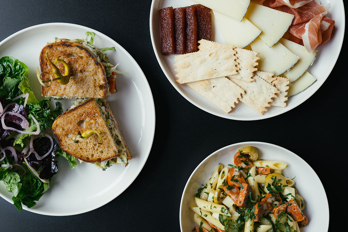 A top down view of plated food including a sandwich and pasta salad