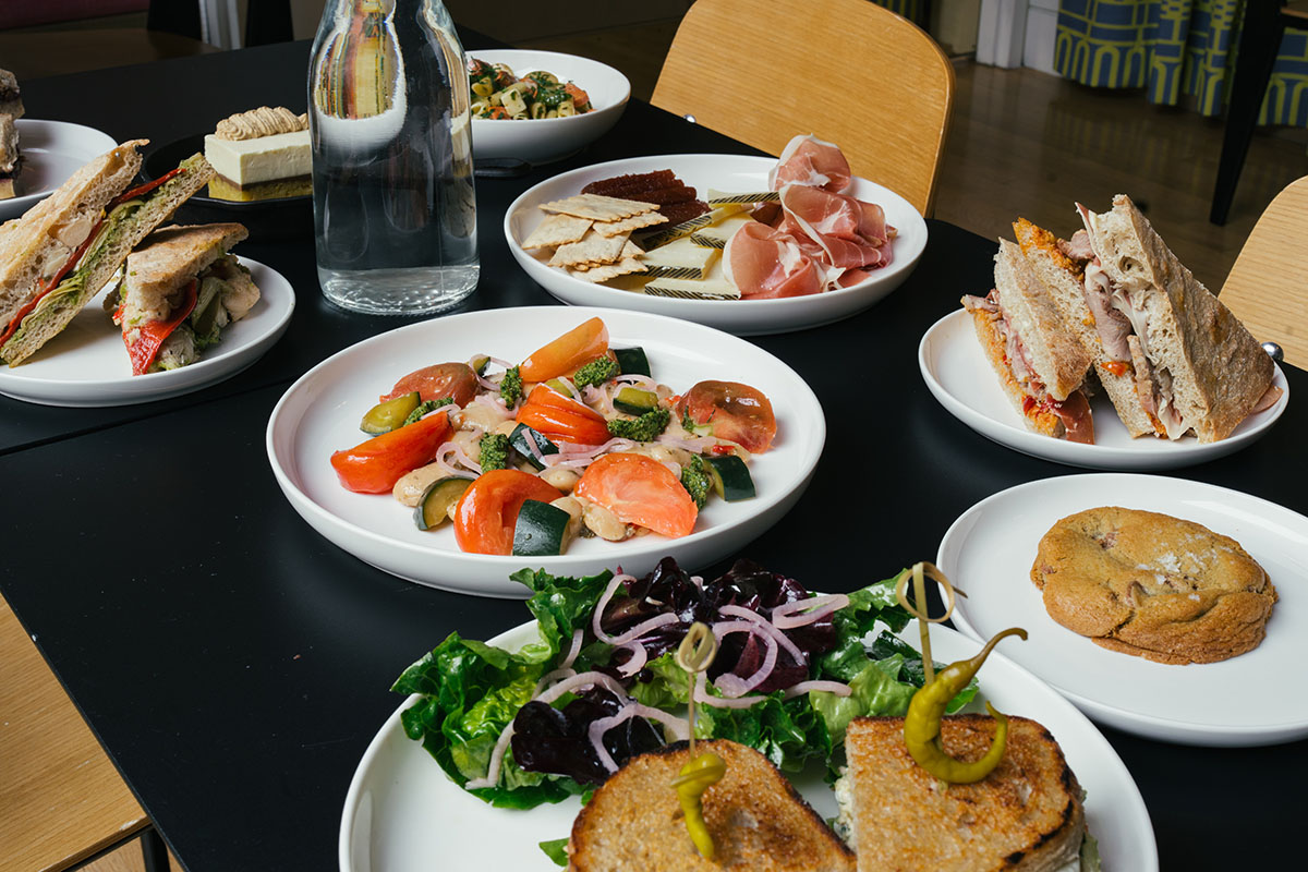 A large number of plates of food on a black table at a restaurant