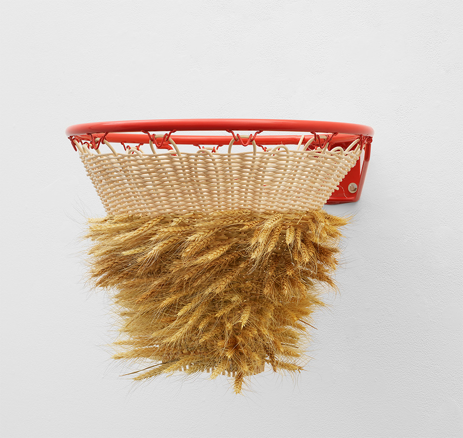 An artwork made of a basketball hoop with stalks of wheat intertwinned in the netting
