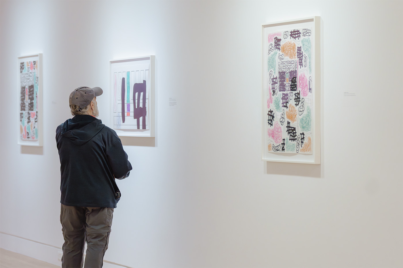 A person looking at paintings on a white wall