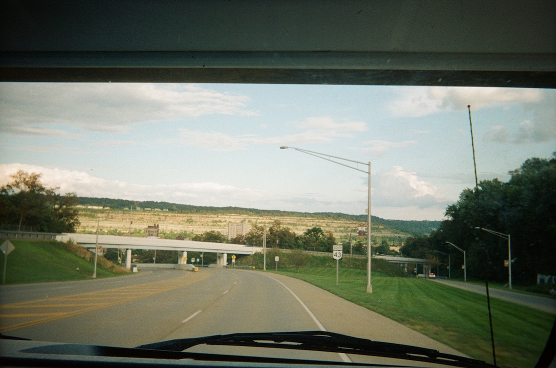 Photo of an empty highway with an overpass looking out the front window of a vehicle