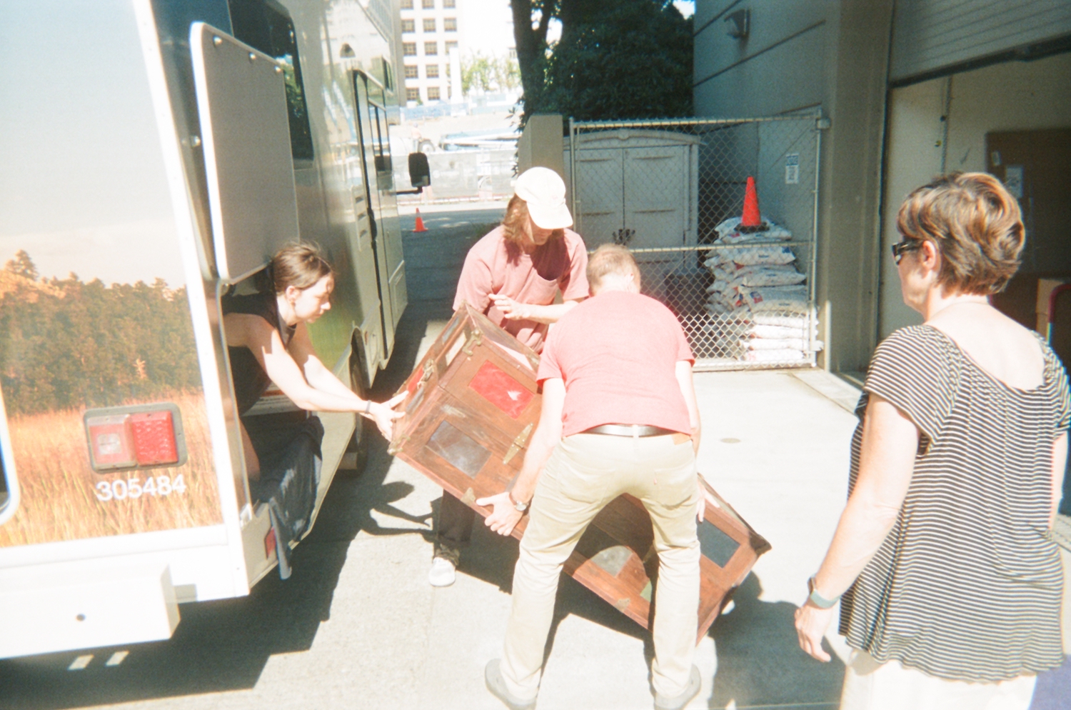Photo of three people unloading a large steamer trunk from an RV while a forth person observes