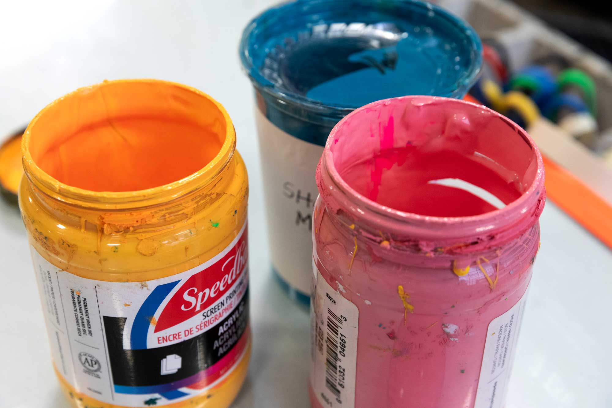 Tubs of bright orange, pink, and blue screenprinting ink