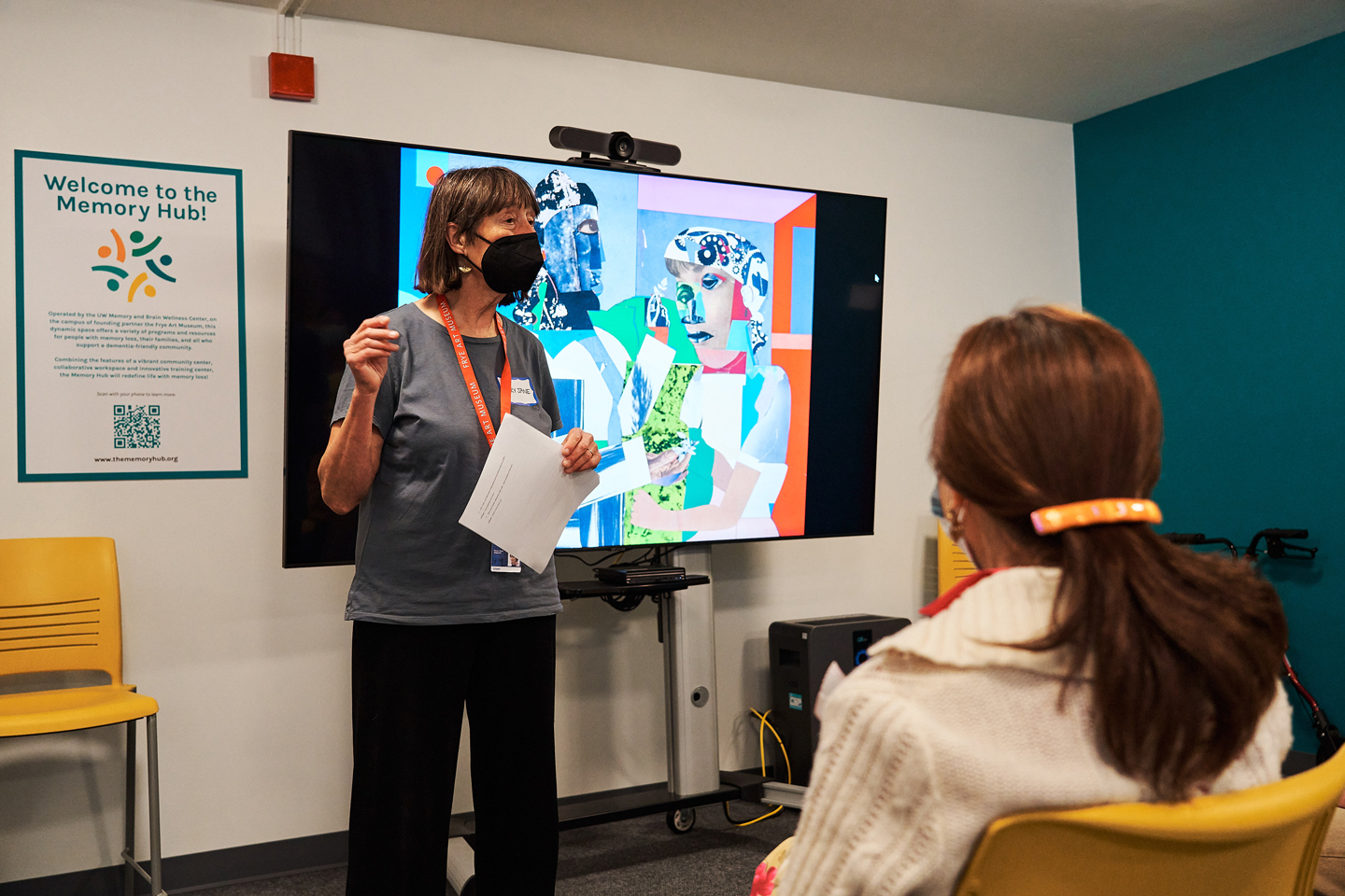 Photo of Mary Jane Knecht leading an artwork discussion in front of a TV monitor with an artwork on it
