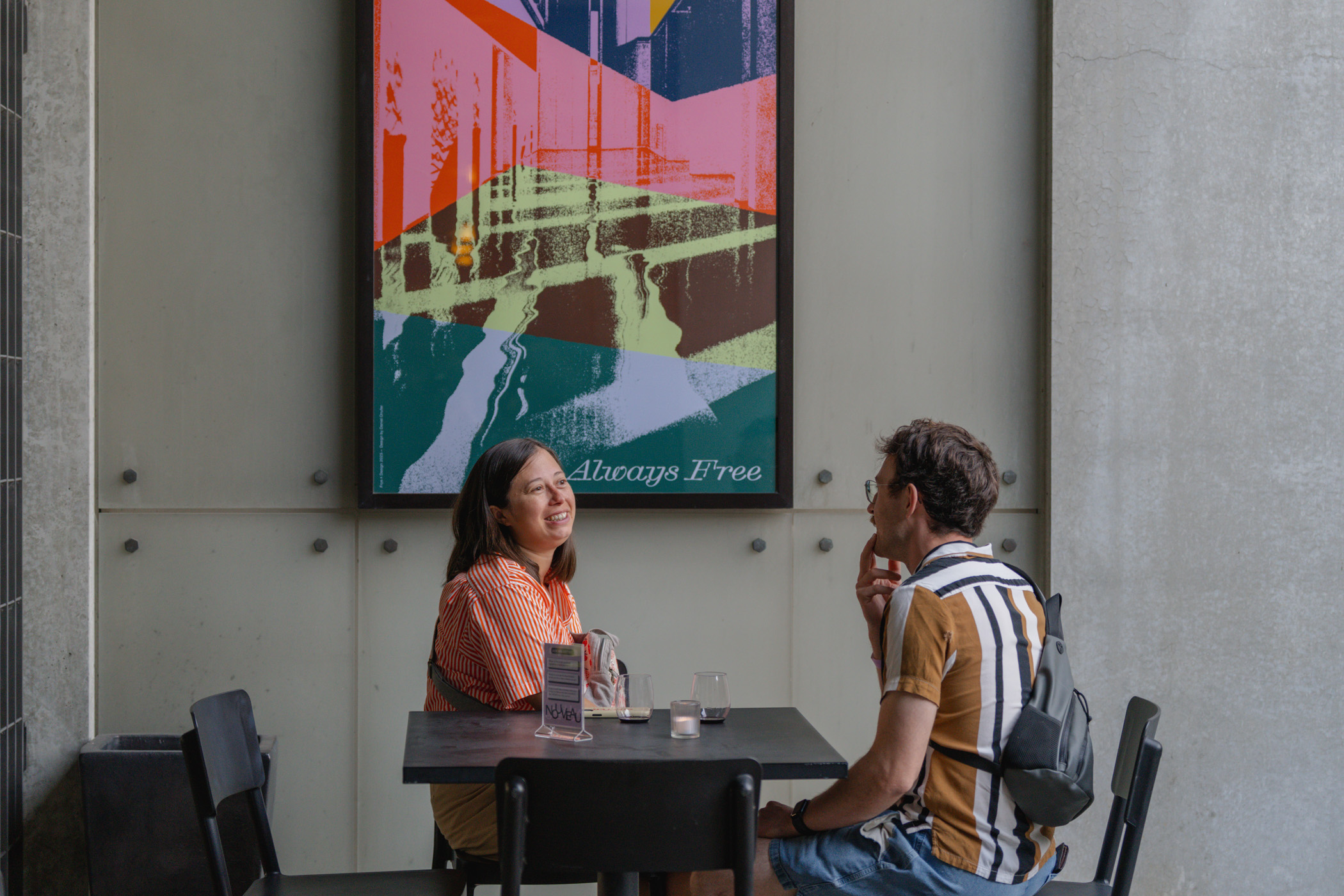 People seated at a table in front of a large, bright poster