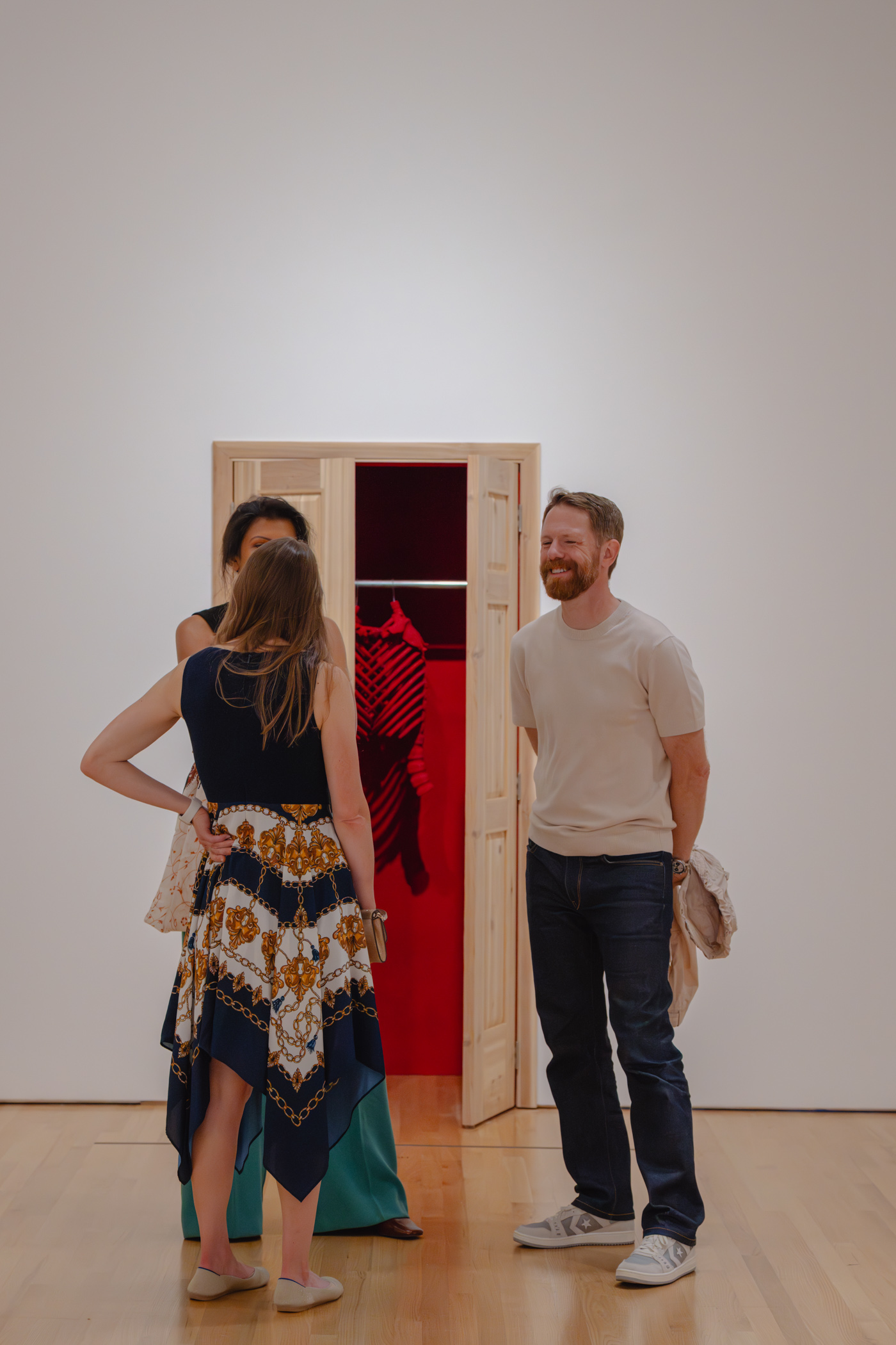People chatting and smiling in front of an artwork with an open door