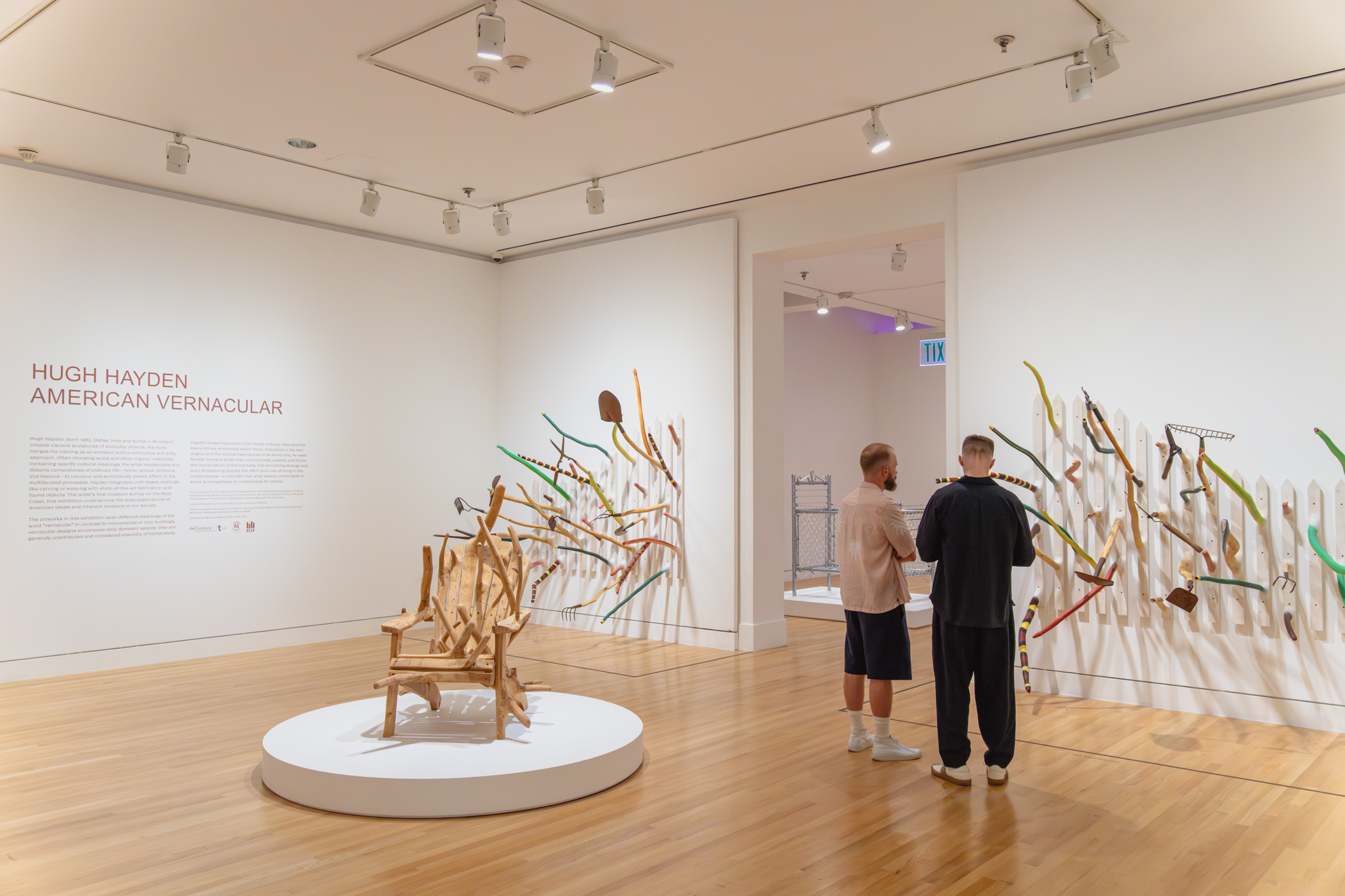 People looking at a wall mounted, sculptural artwork