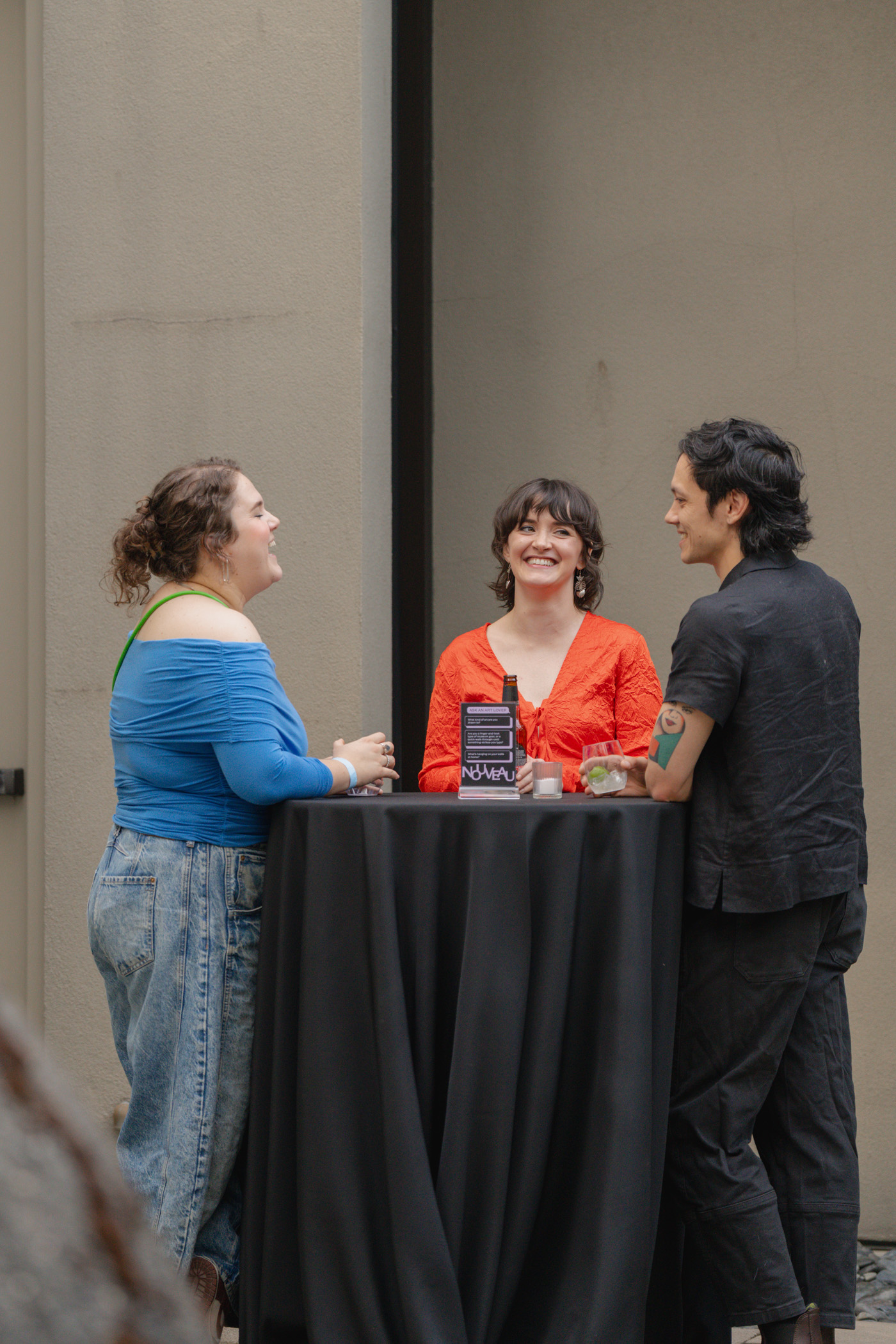 People standing and chatting by a tall banquet table