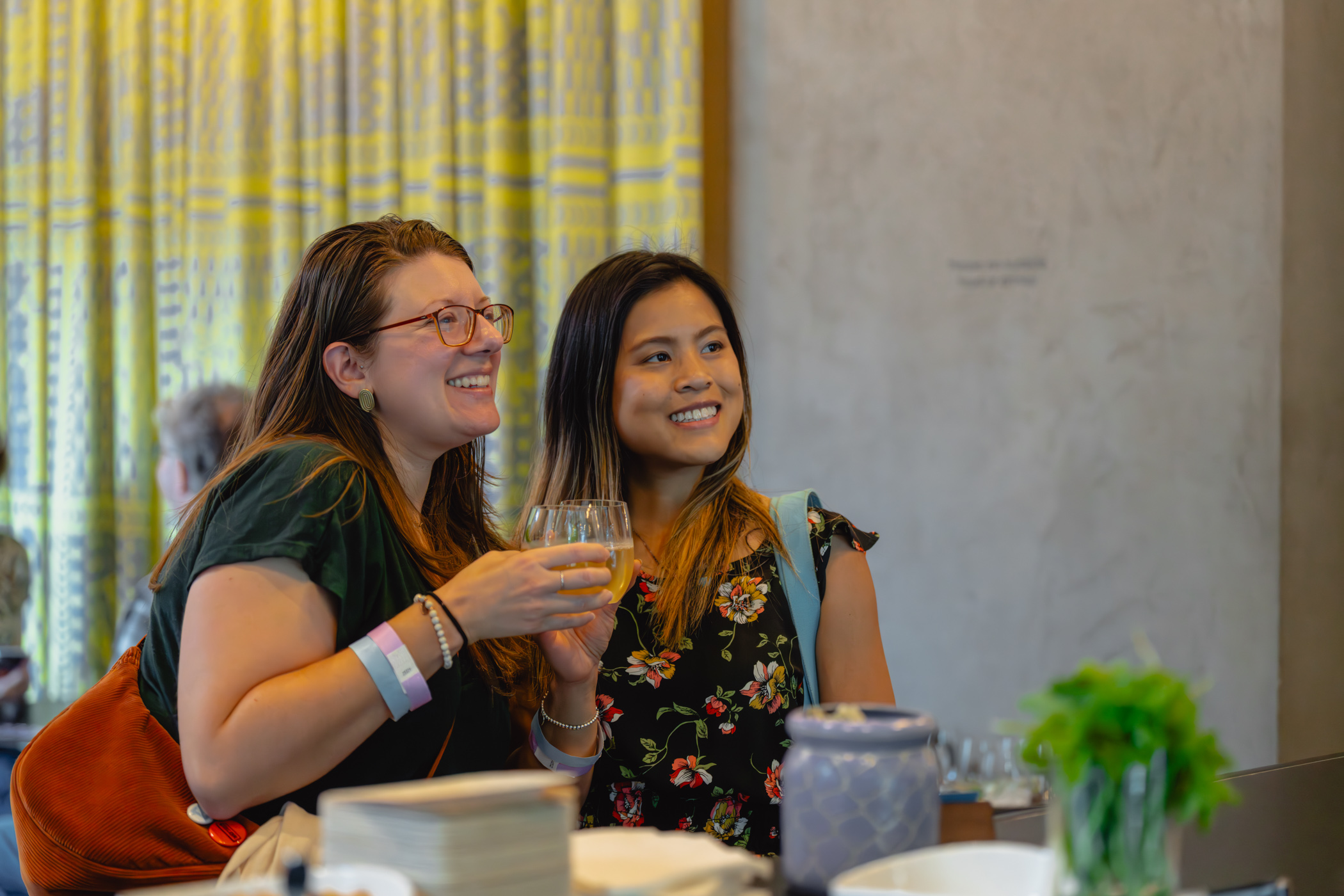 People smiling and holding drinks while posing for someone out of the frame taking a photo