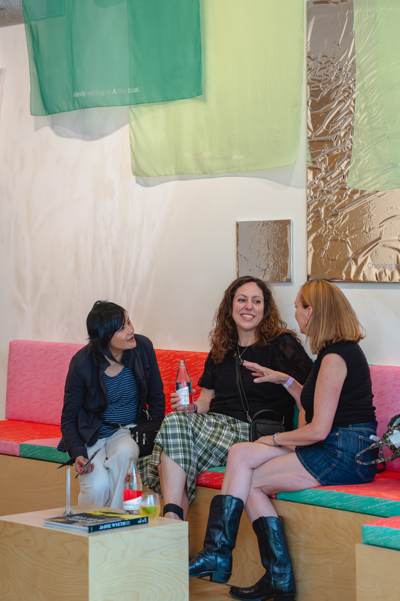 A group of people chatting while seating on a colorful indoor bench