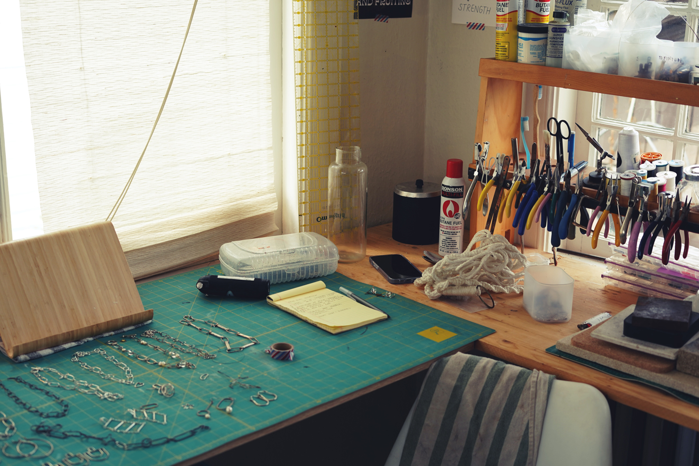 Photo of a jewelry workspace with tools on the right and silver jewelry on the table