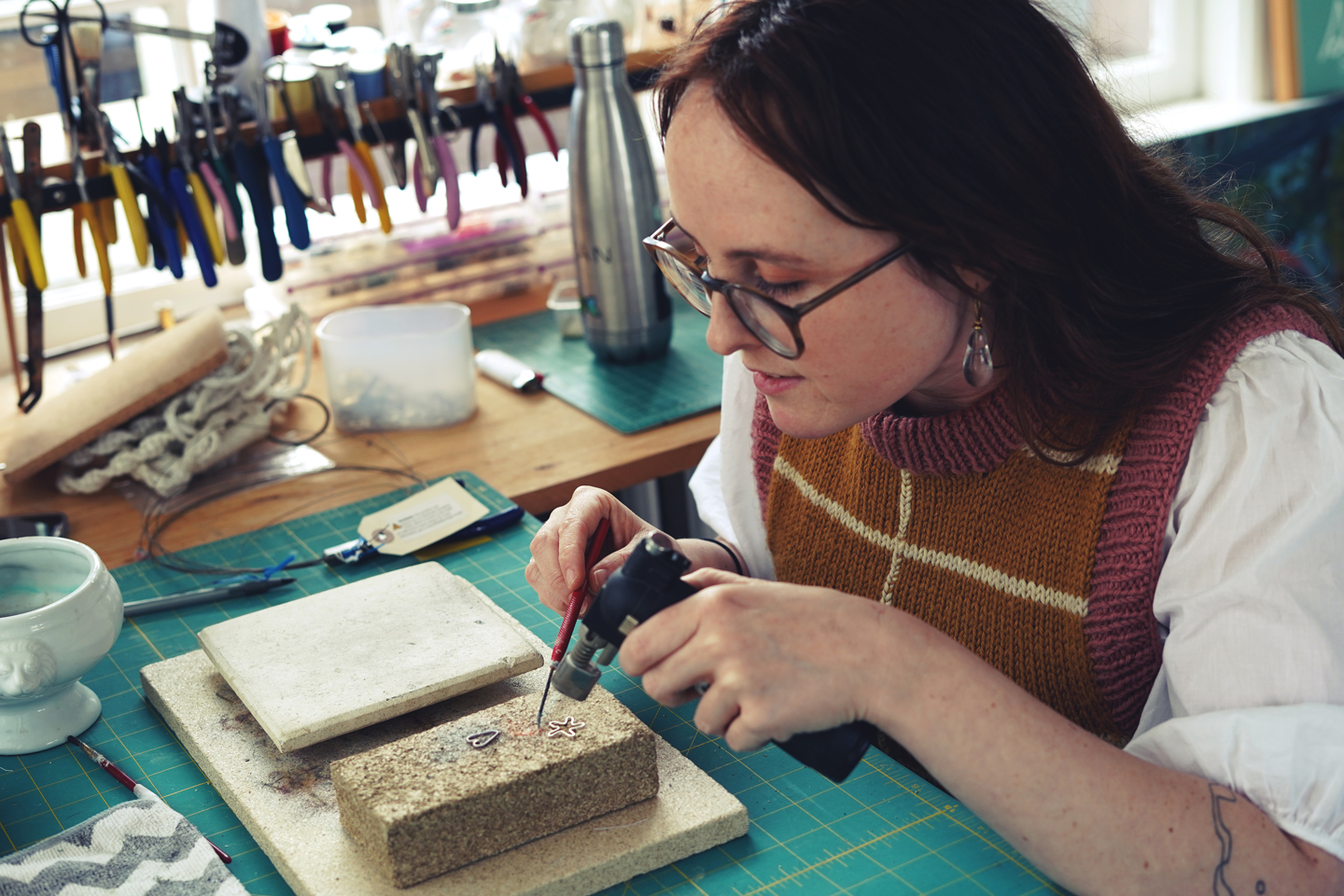 Photo of Devon Simpson using a soldering torch on two small pieces of silver