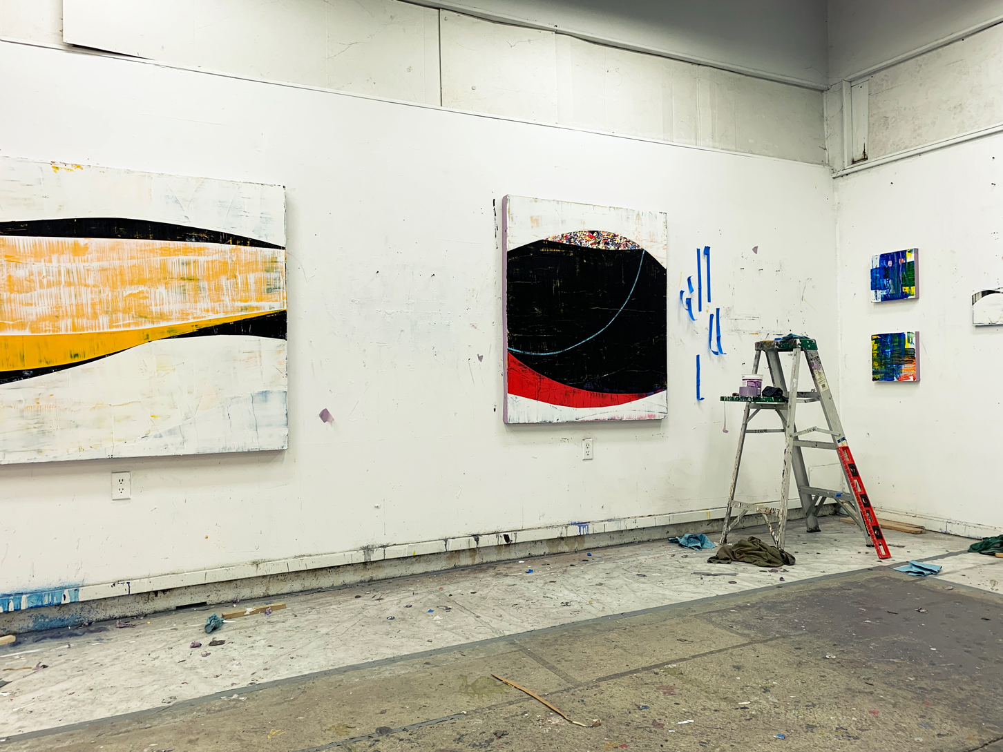 Photo of Ken Kelly's studio with two large paintings and two small paintings on the walls and a small step ladder in the corner