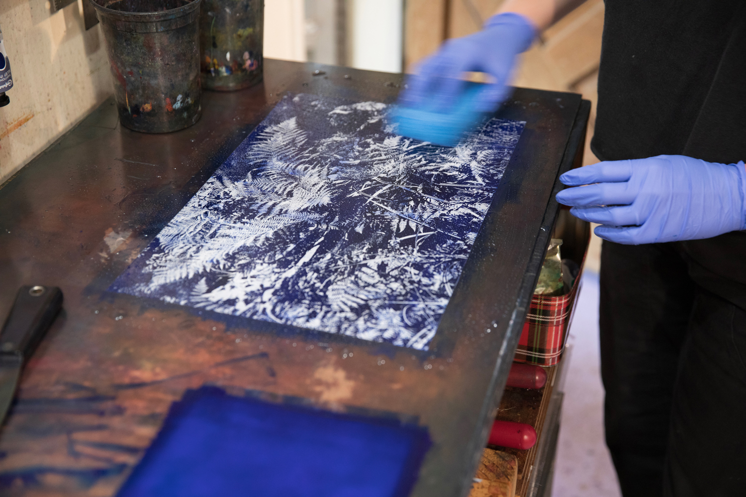 Close-up photo of Shannon Bodrogi's hands holding a sponge in the process of making a paper lithograph