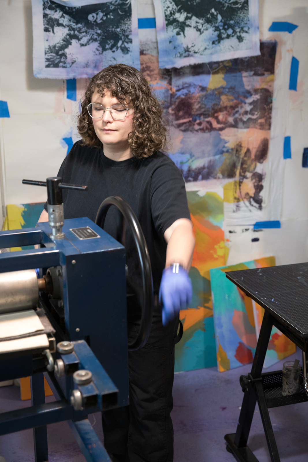 Photo of Shannon Bodrogi in their studio in the process of making a paper lithograph