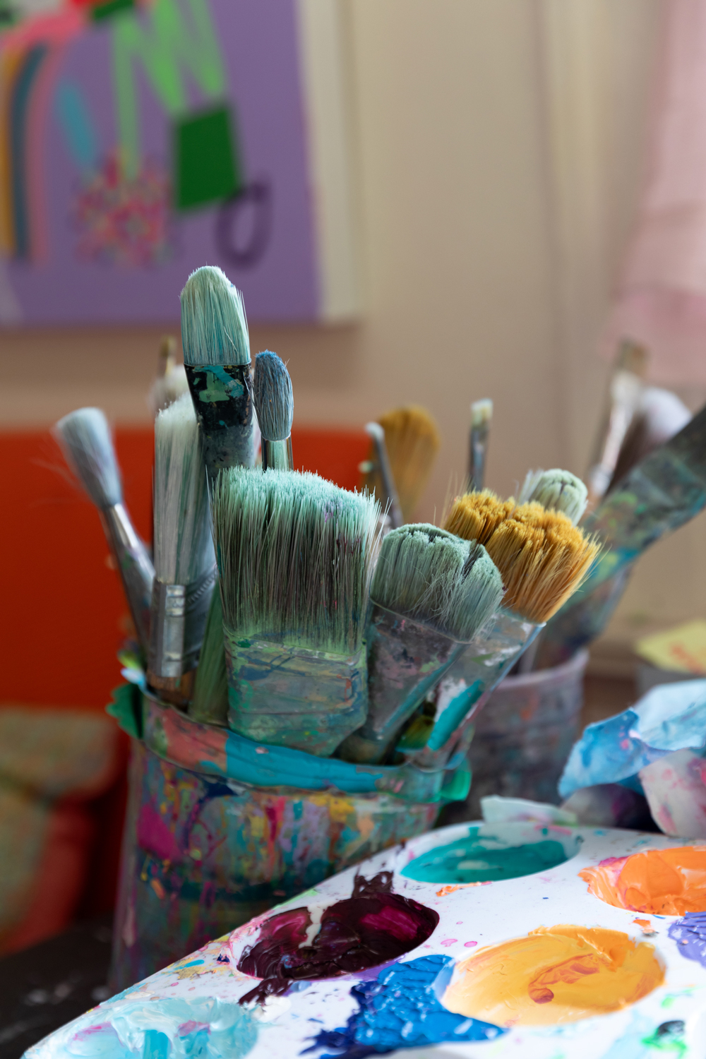 Photo of paintbrushes in a cup next to a palatte