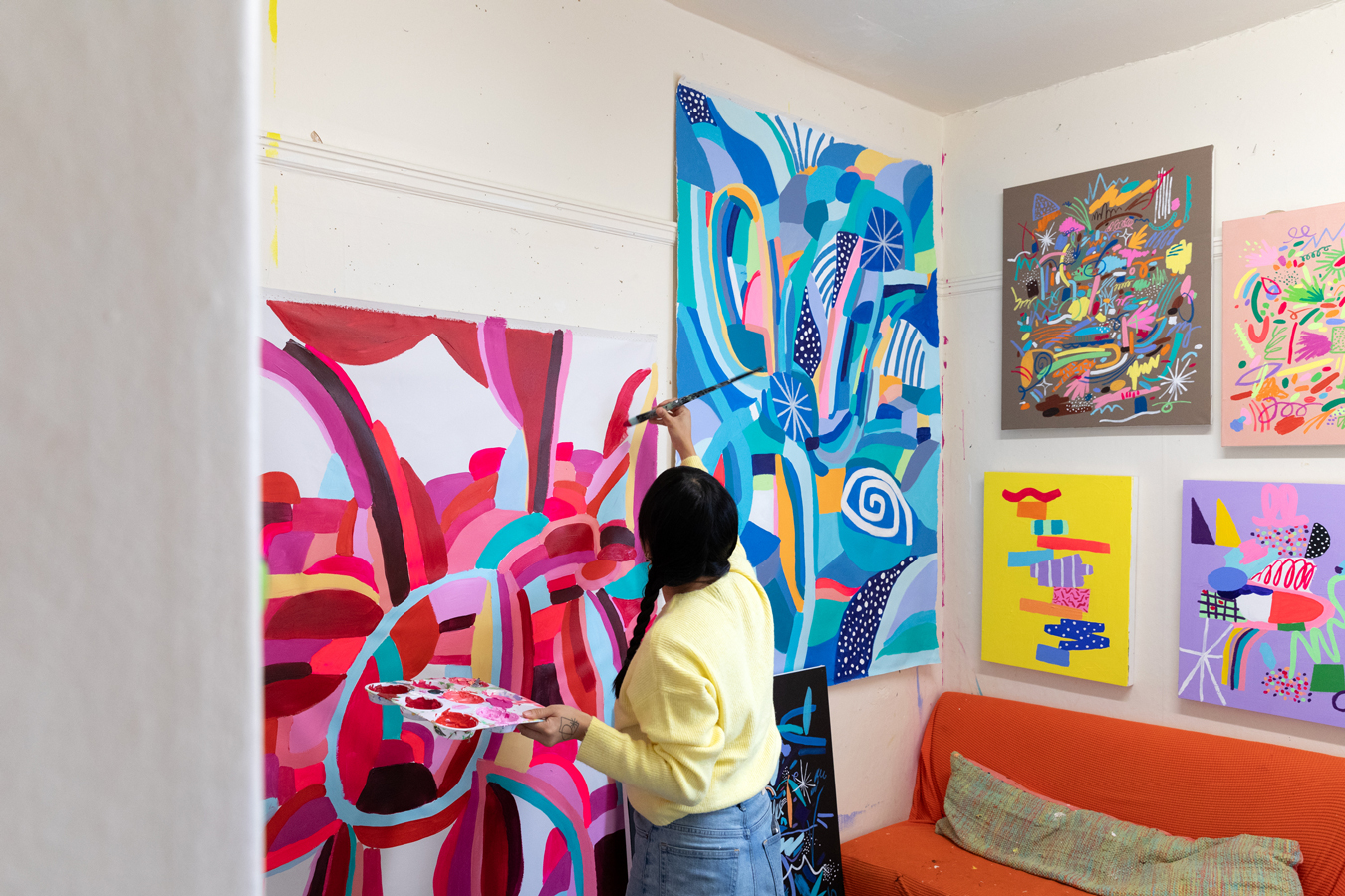 Photo of Nikita Ares, a woman with dark brown hair, painting with bright pink paints