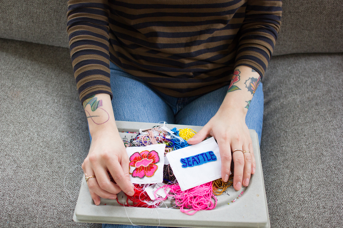 Photo of multiple beaded pieces and beads on a lap being held by two hands