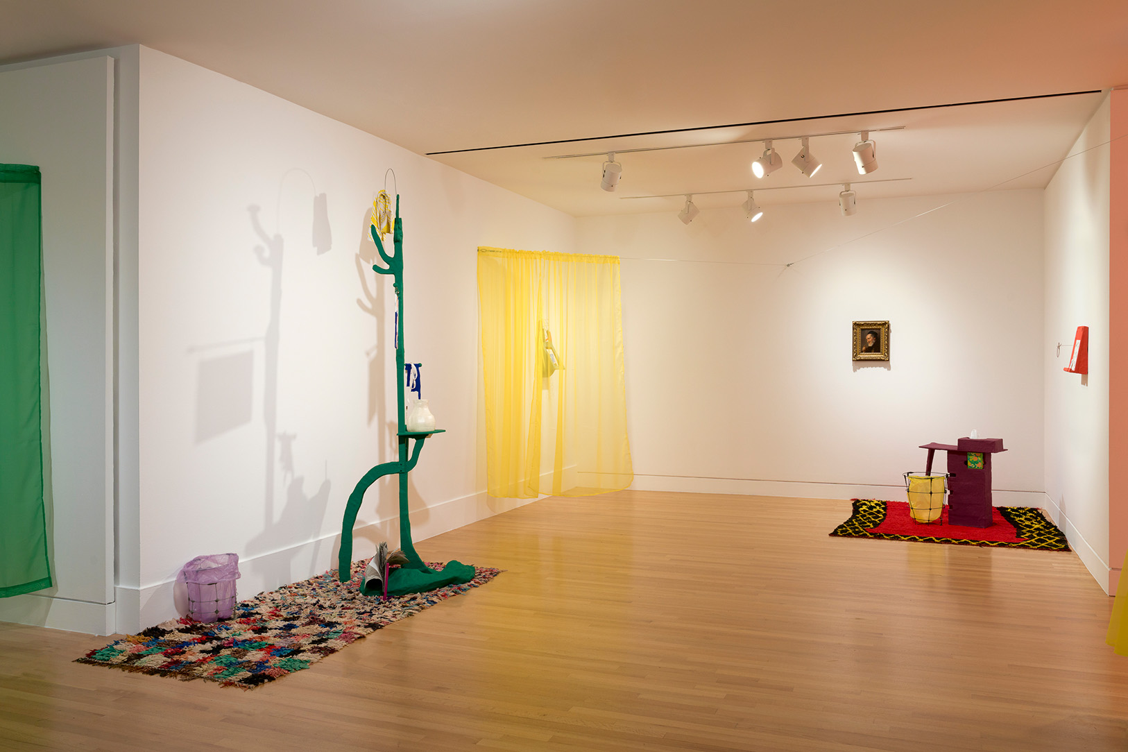 A small alcove in an art gallery with a variety of abstract, sculptural artworks and hanging curtains