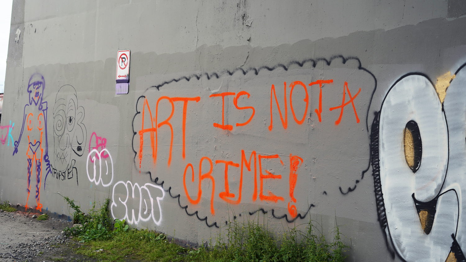 Photo of a wall with graffiti, one reads "Art is not a crime"