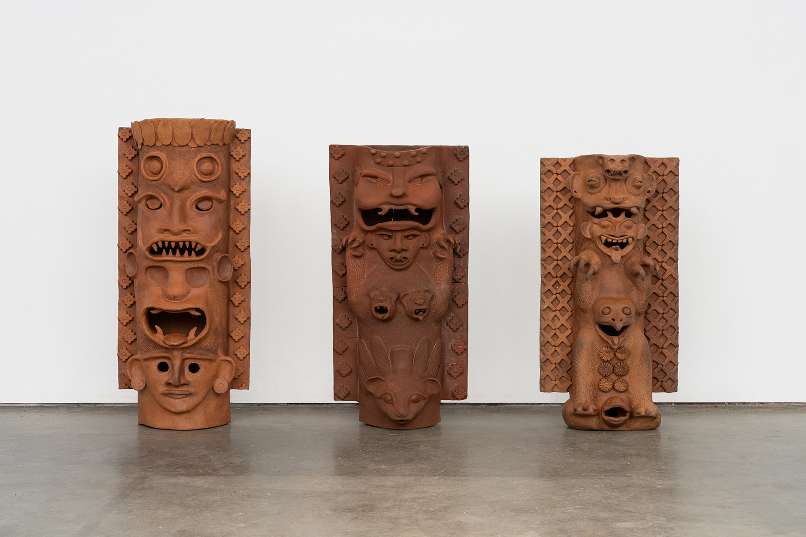 Three large, freestanding ceramic sculptures with animal faces and motifs