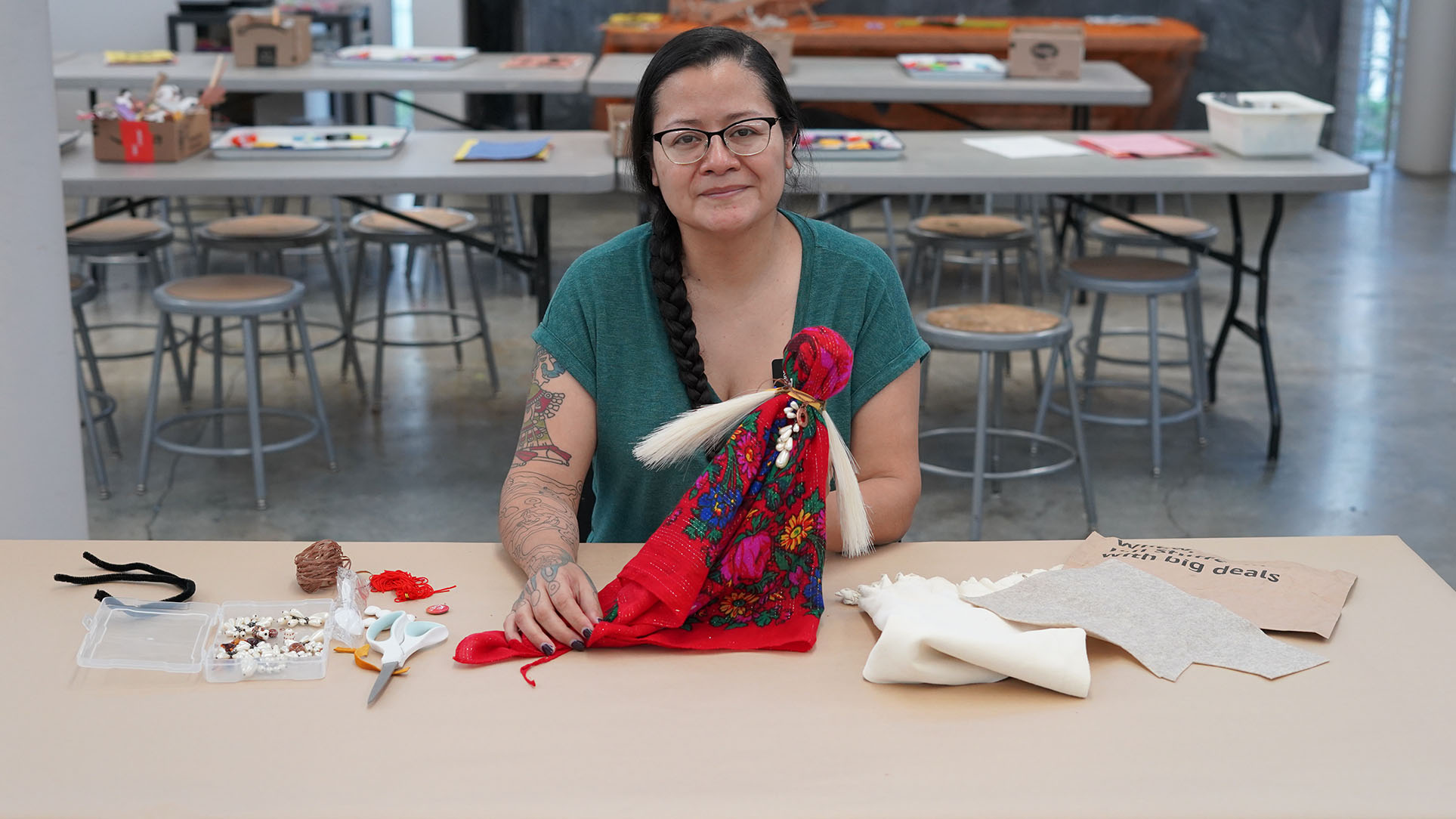 A woman sitting at a table holding a doll made from crafting materials