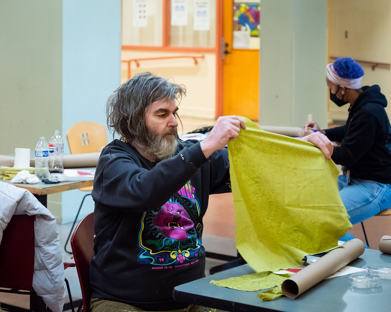A person sitting at a table holding up a piece of fabric
