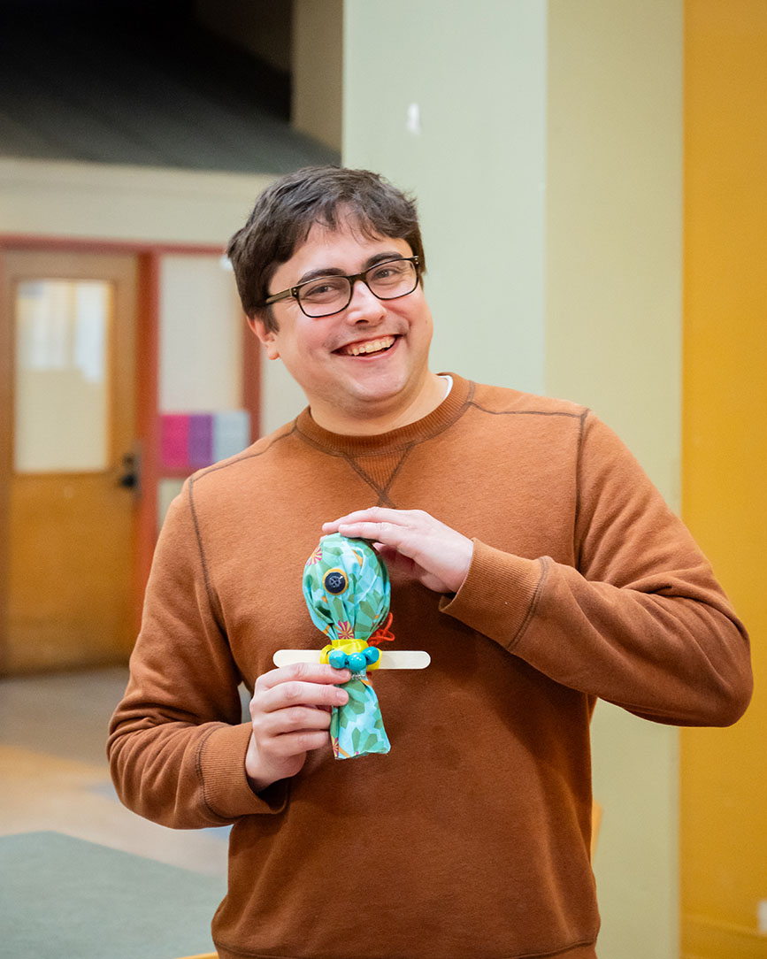 A person holding a doll made from crafting materials