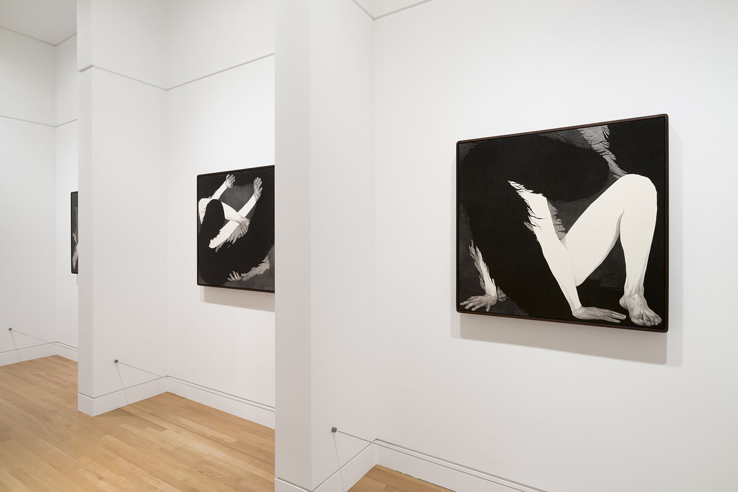 Photo of two black and white figurative drawings on a white gallery wall