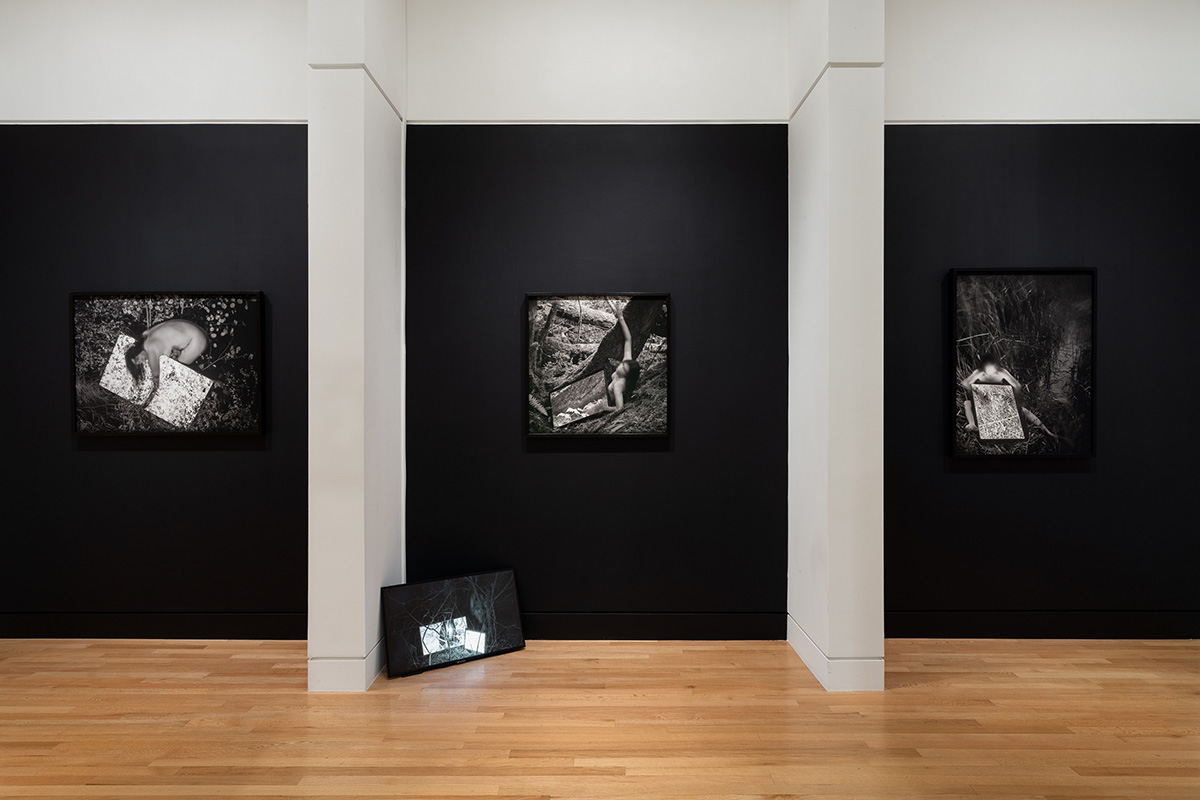 A series of black and white photographs mounted in black frames on a long wall in a museum gallery space