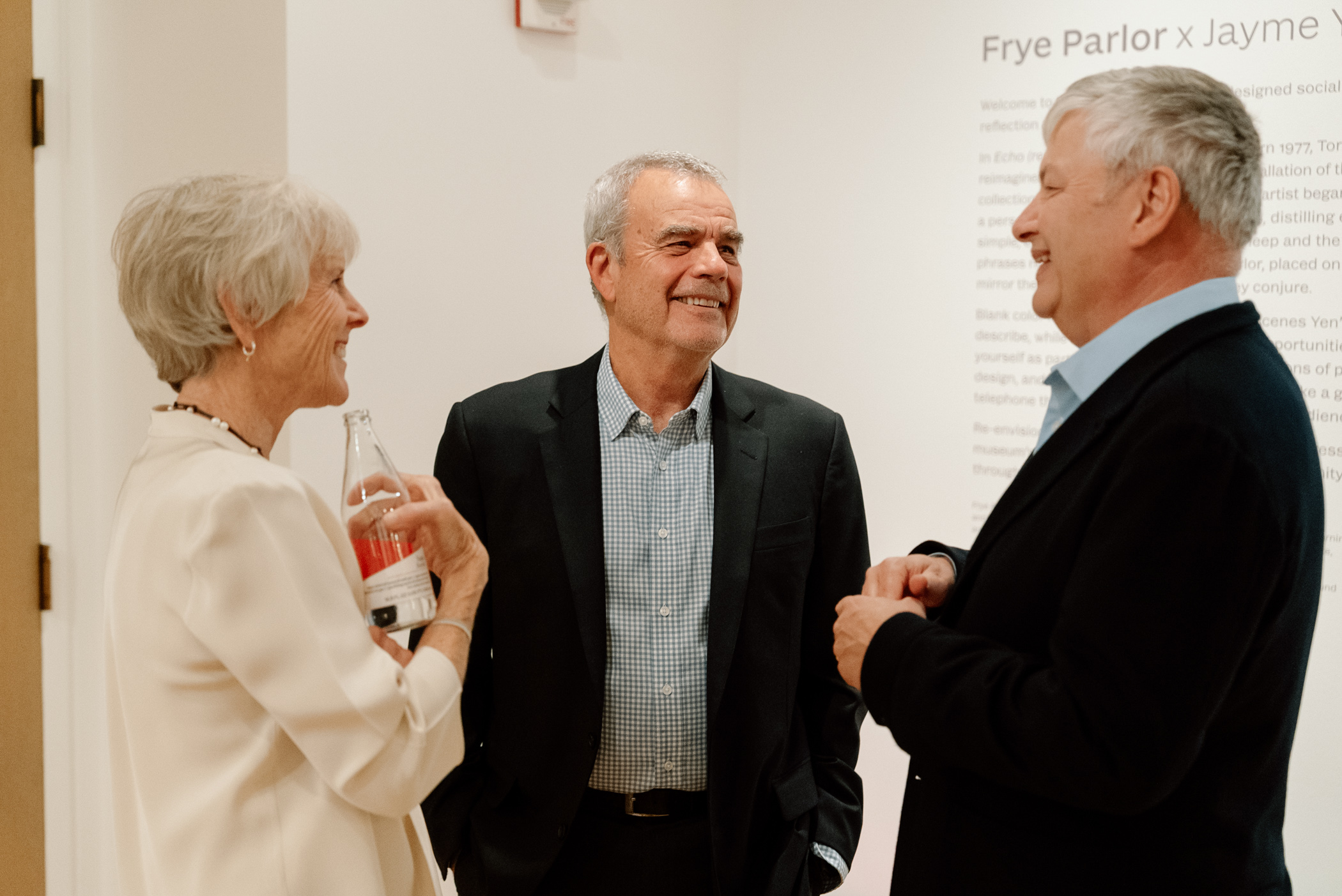 Three people in formal clothing standing and chatting