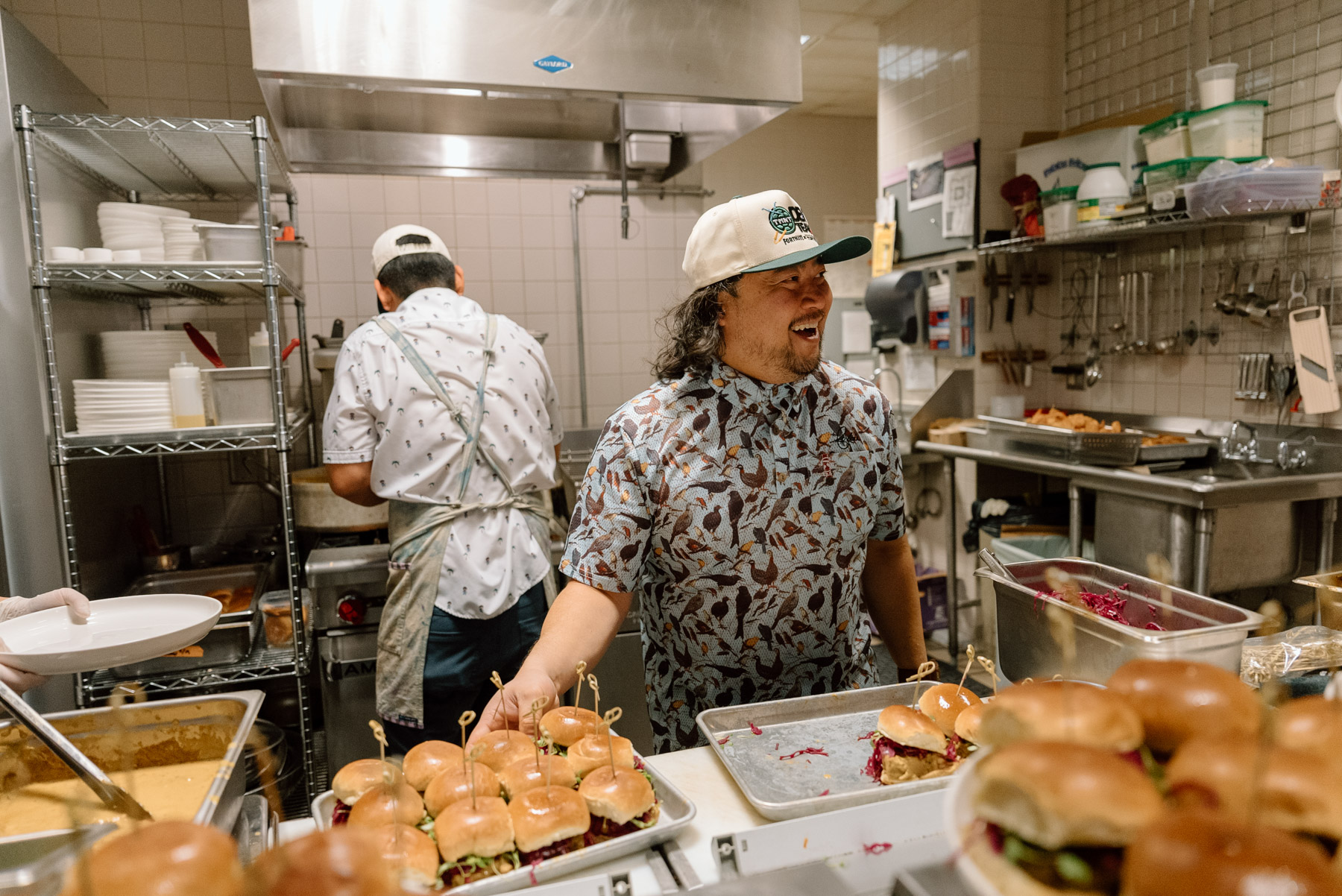 A person in a kitchen smiling and holding a tray of food