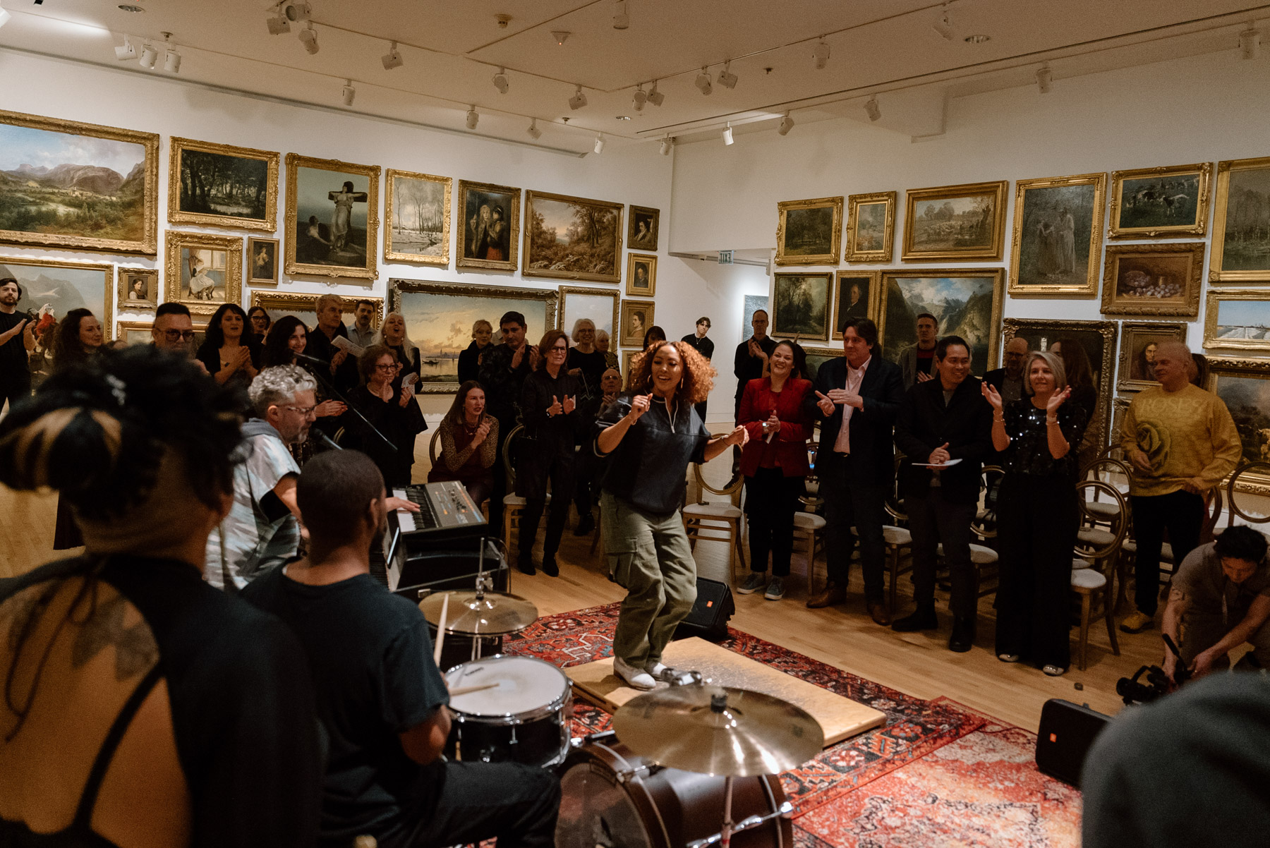 People watching a tap dancer in a large room filled with opulent gold paintings