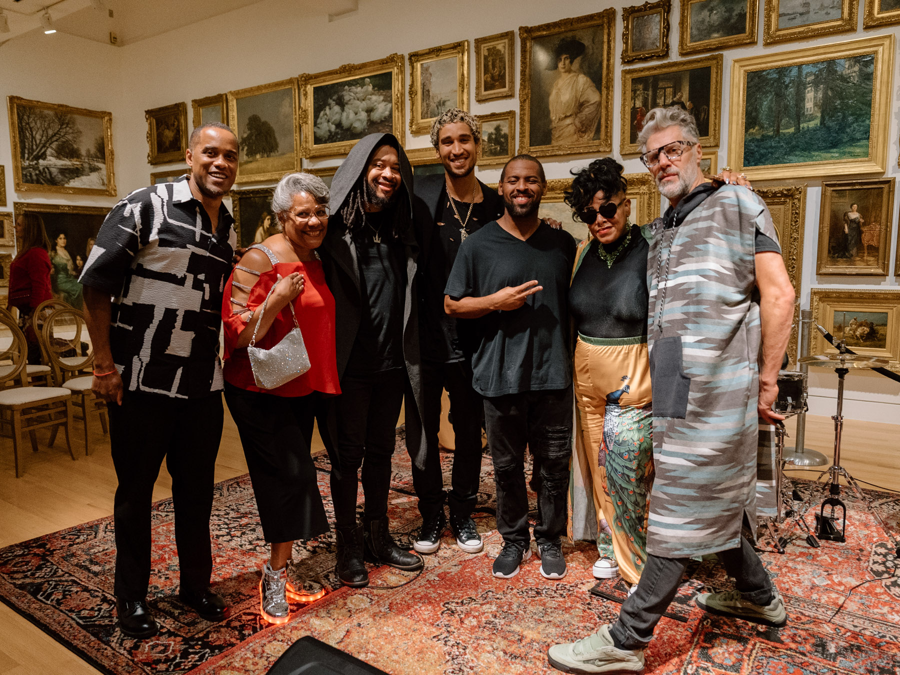 People posed in a row and smiling in a room full of gold paintings