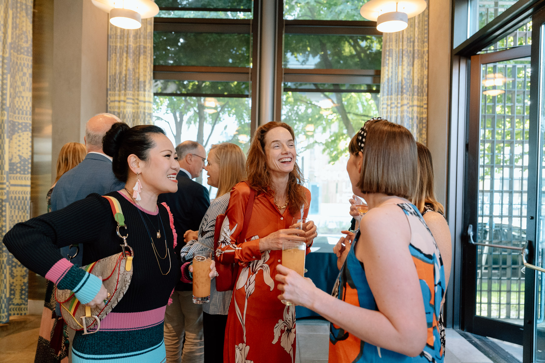 A group of women smiling and chatting while holding drinks in a well-lit café space