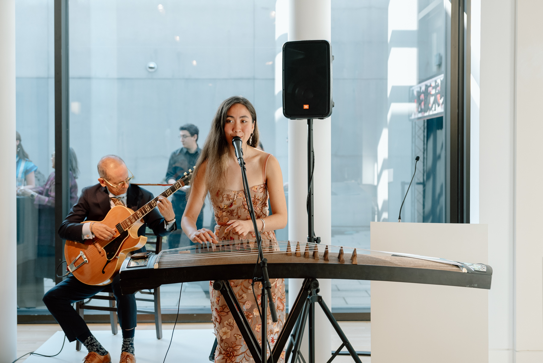 A woman playing a horizontal string instrument in front of a man playing a guitar