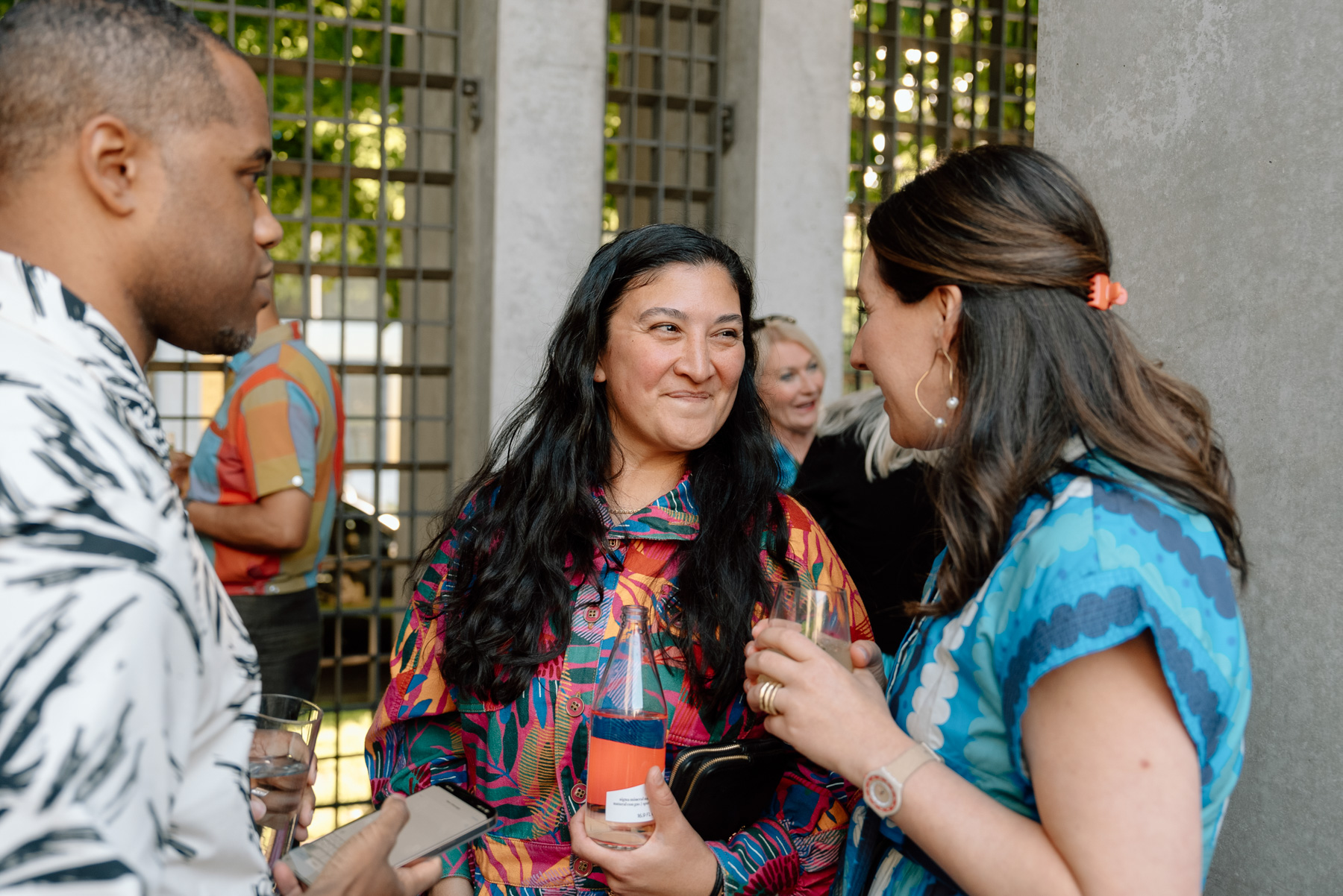 Three people smiling and chatting in an outdoor space