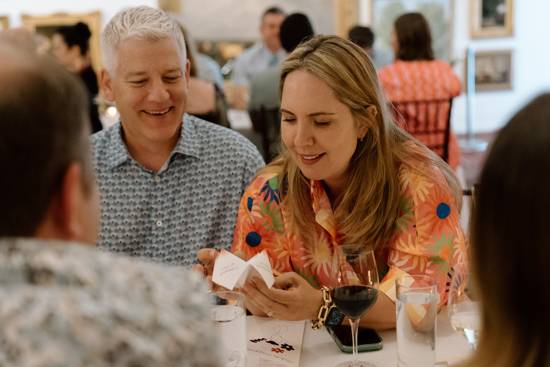 Two people at a long dinner table looking at a fortune teller