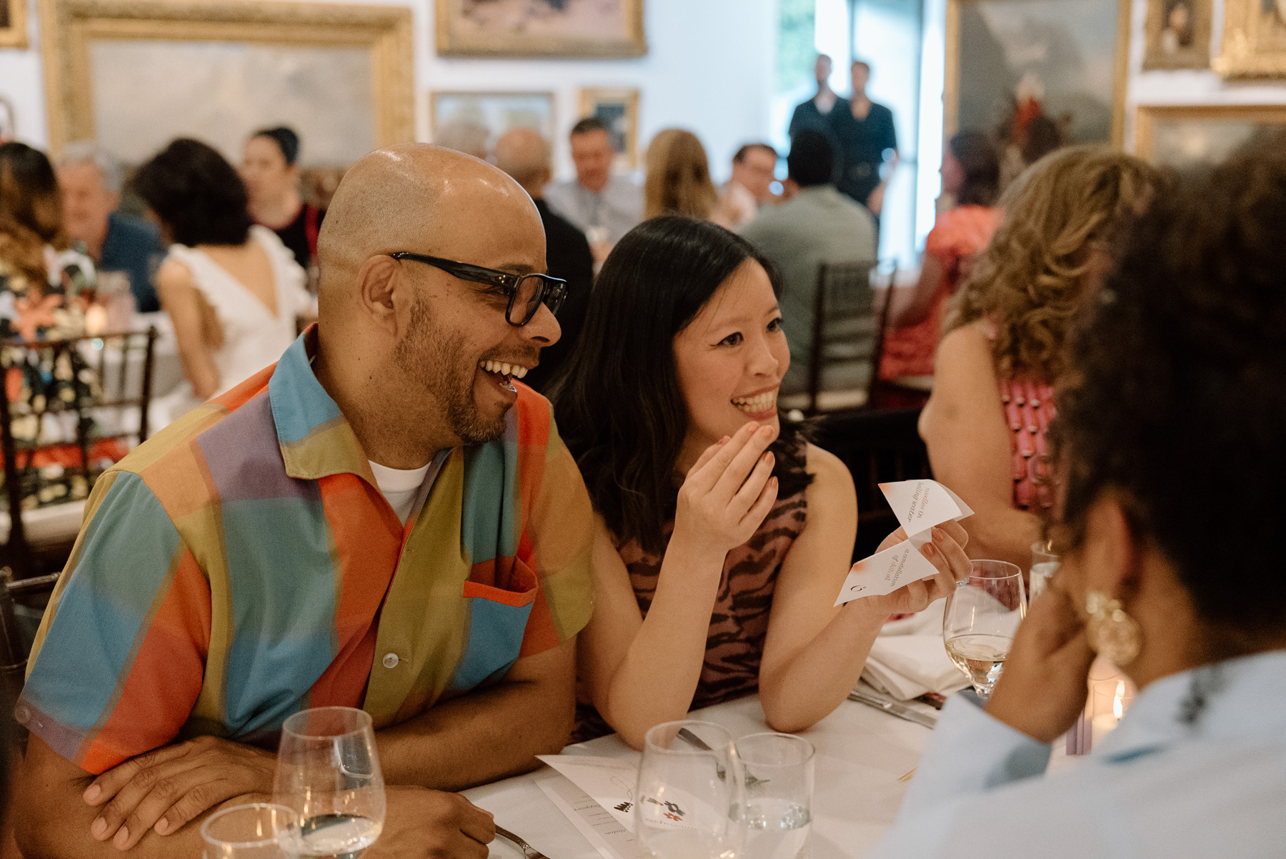 People smiling and laughing while talking to people across from them at a long dinner table