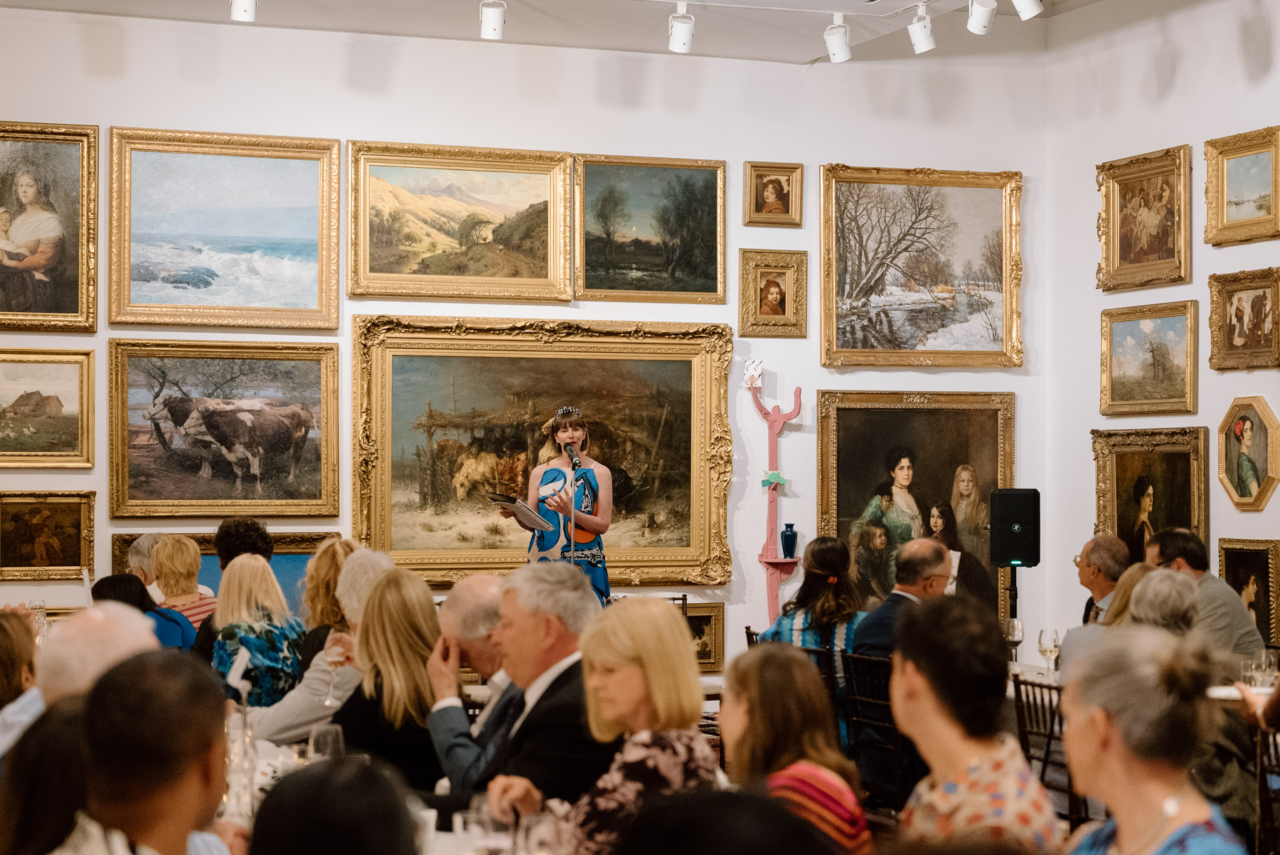 People seated at long dinner tables in a large gallery room