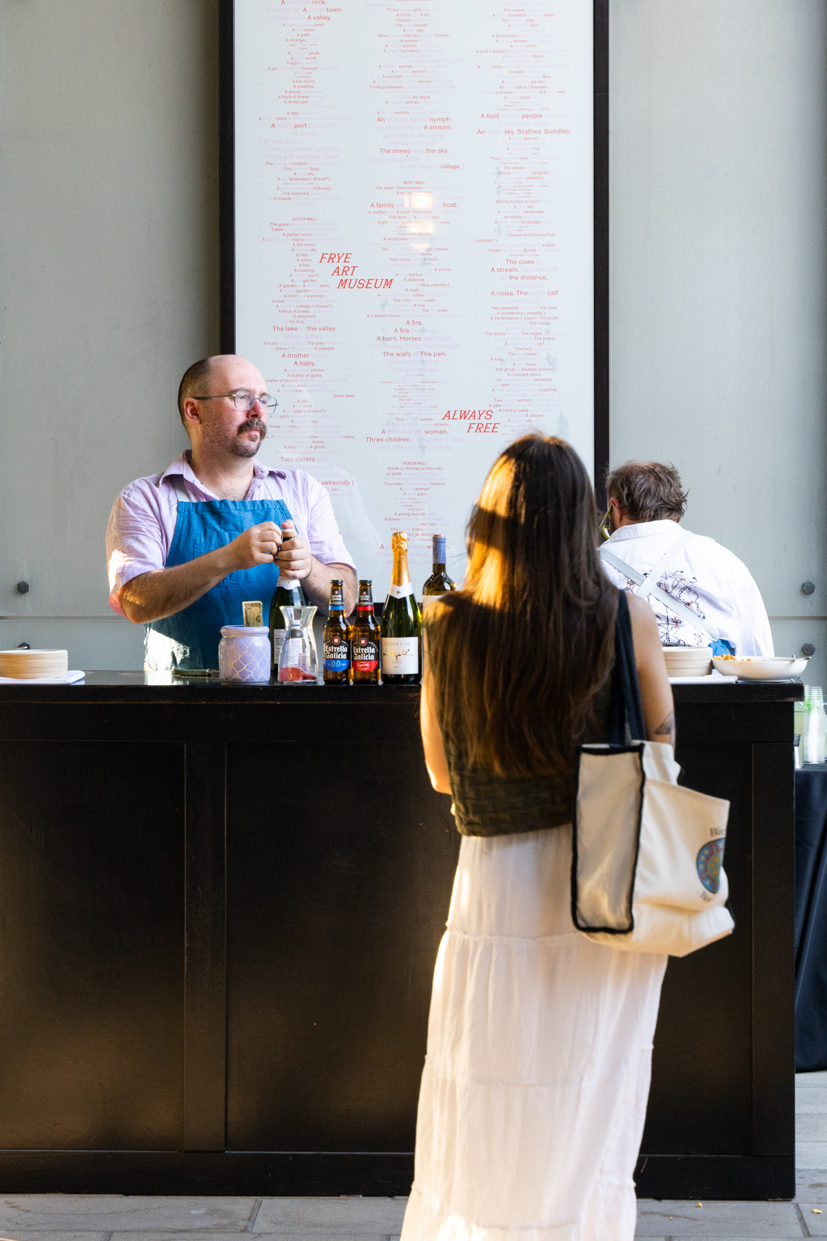 A person standing in front of a bar outside in front of a poster